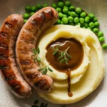 Banger sausage recipe: grilled sausages served with mashed potatoes, peas, and gravy